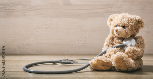 Teddy bear and a stethoscope on a wooden floor photo