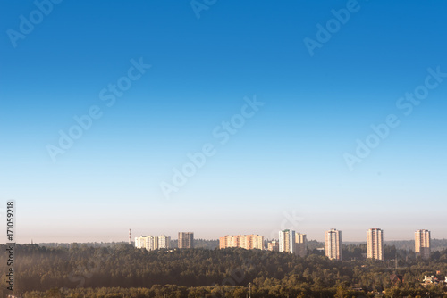 Fototapeta Naklejka Na Ścianę i Meble -  Beautiful autumn forest with a view of skyscrapers in the distance, view from unmanned quadrocopter.