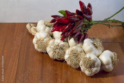 hot peppers red and garlic braid on wooden background