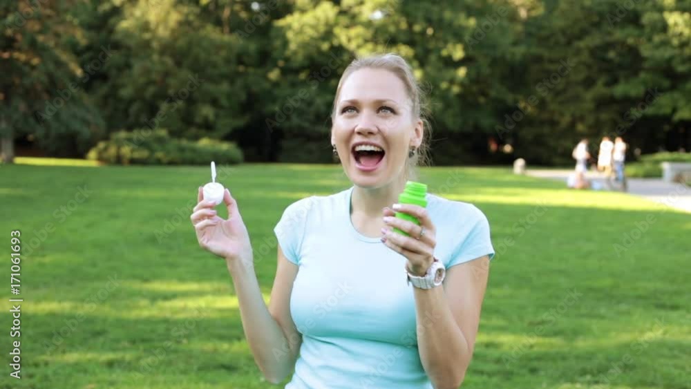 A woman blows bubbles. Girl blowing soap bubbles in the park. A woman blows bubbles. Girl blowing soap bubbles in the park.