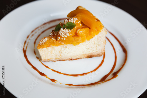 Cheesecake with caramel and peaches on a white plate