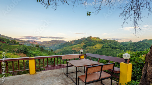 Table and chairs on the terrace for dining and enjoy the beautiful natural landscape of forest and mountains in the morning atmosphere at Doi Mae Salong view point in Chiang Rai Province, Thailand