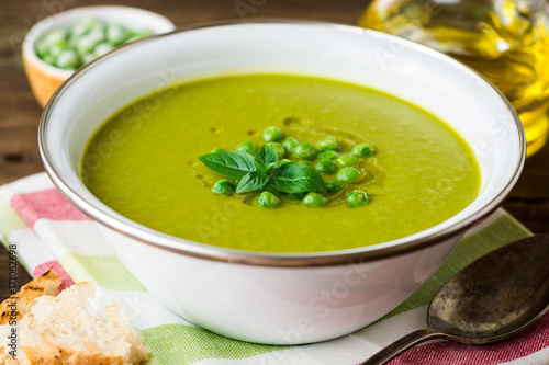 Green pea soup in bowl on wooden table