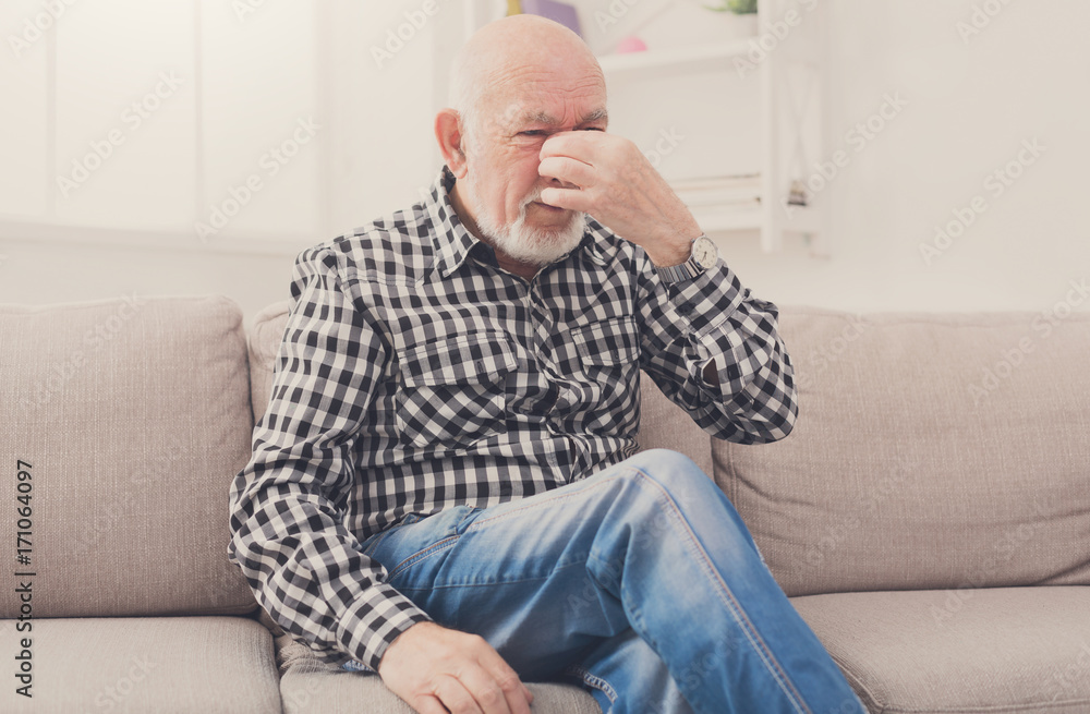 Elderly man with headache pinching back of nose Elderly man with headache pinching back of nose