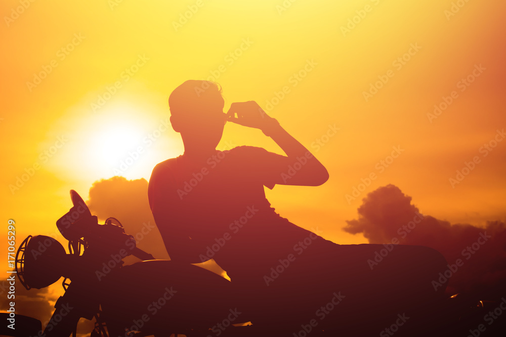 Silhouette of man and a motorcycle with sunset background.