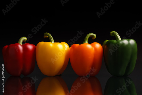 Stampa su Tela Group of bell peppers on black reflective background.