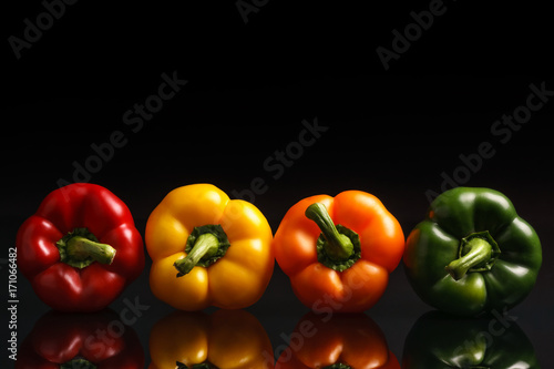 Group of bell peppers on black reflective background.