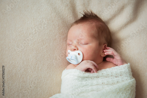 Vászonkép Cute newborn baby sleeping on white blanket with a pacifier