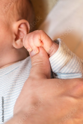 ein Baby hält den Daumen vom Elternteil