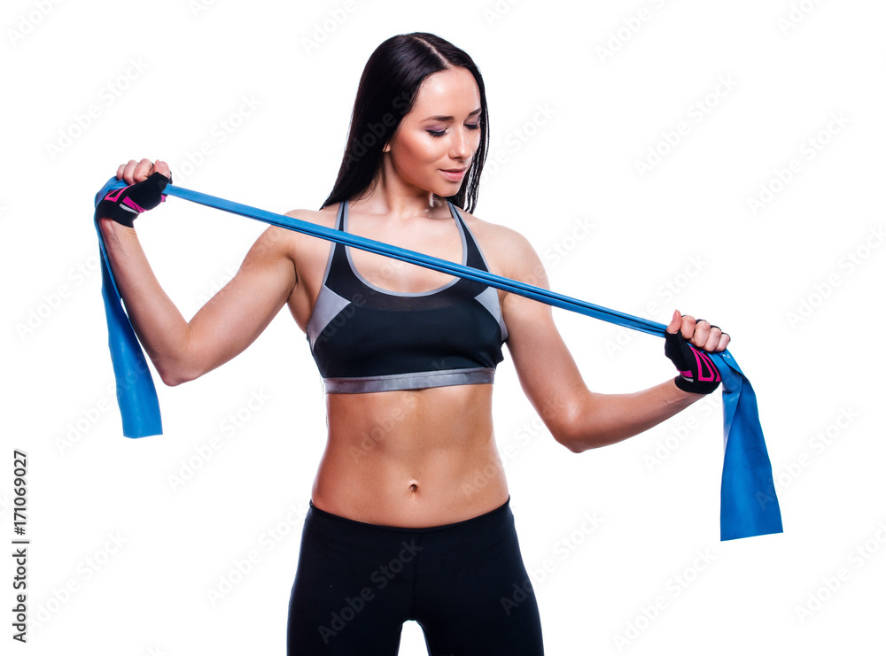 Fitness girl performs exercises with resistance band. Attractive young woman doing exercises with expander over white background. Fitness girl performs exercises with resistance band. Attractive young woman doing exercises with expander over white background.