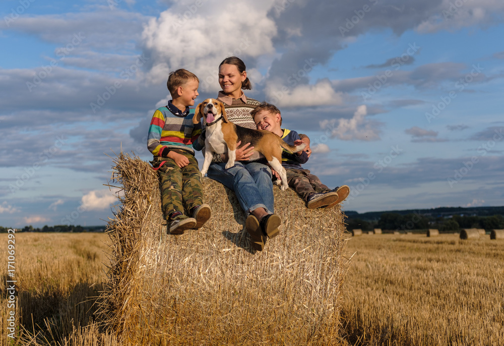 mother, two sons and a Beagle dog on bale of straw