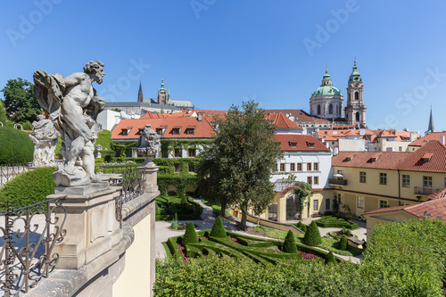 Statues at the Vrtba Garden (Vrtbovská zahrada) and view of St. Nicholas Church and other old buildings at the Mala Strana District (Lesser Town) in Prague, Czech Republic on a sunny day. photo