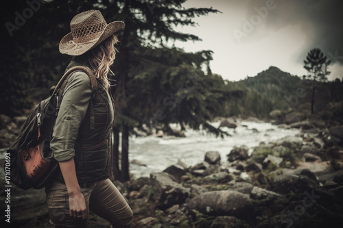 Beautiful woman hiker near wild mountain river. photo