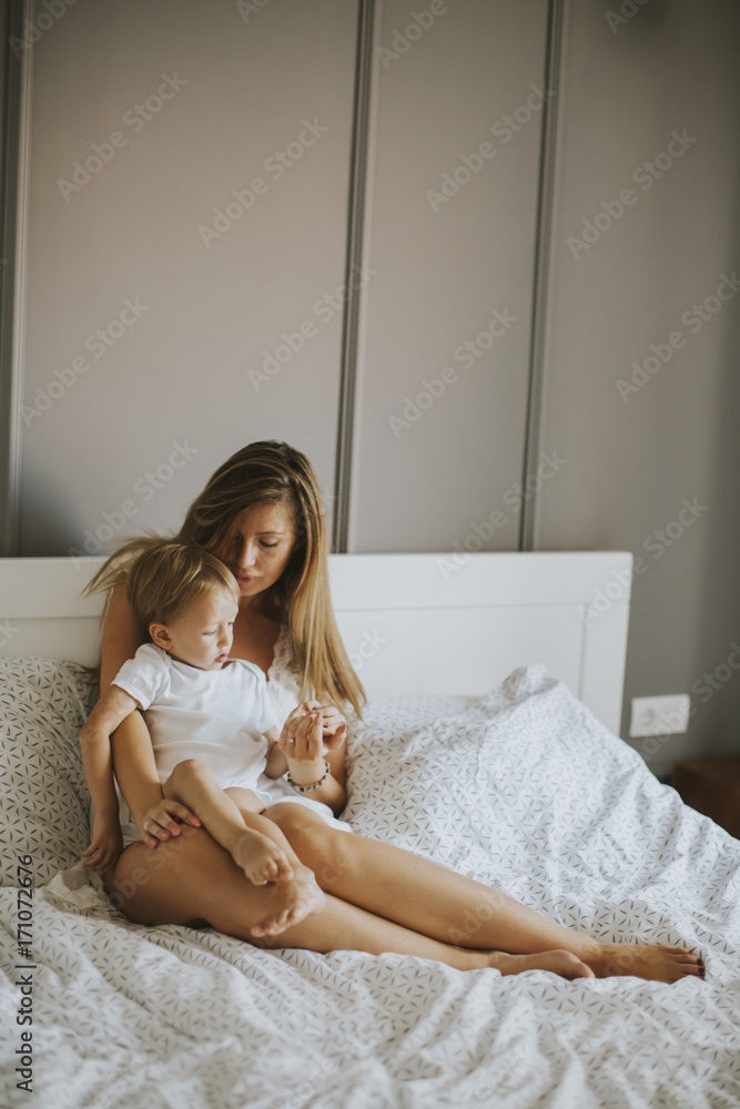 Mother playing with little boy on bed Mother playing with little boy on bed