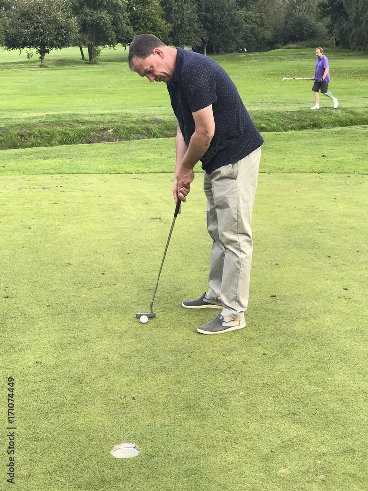 Fototapeta premium Golfspieler beim Putten auf einem Golfplatz