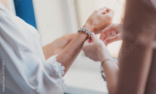 подруга помогает невеста одевать браслет на руку