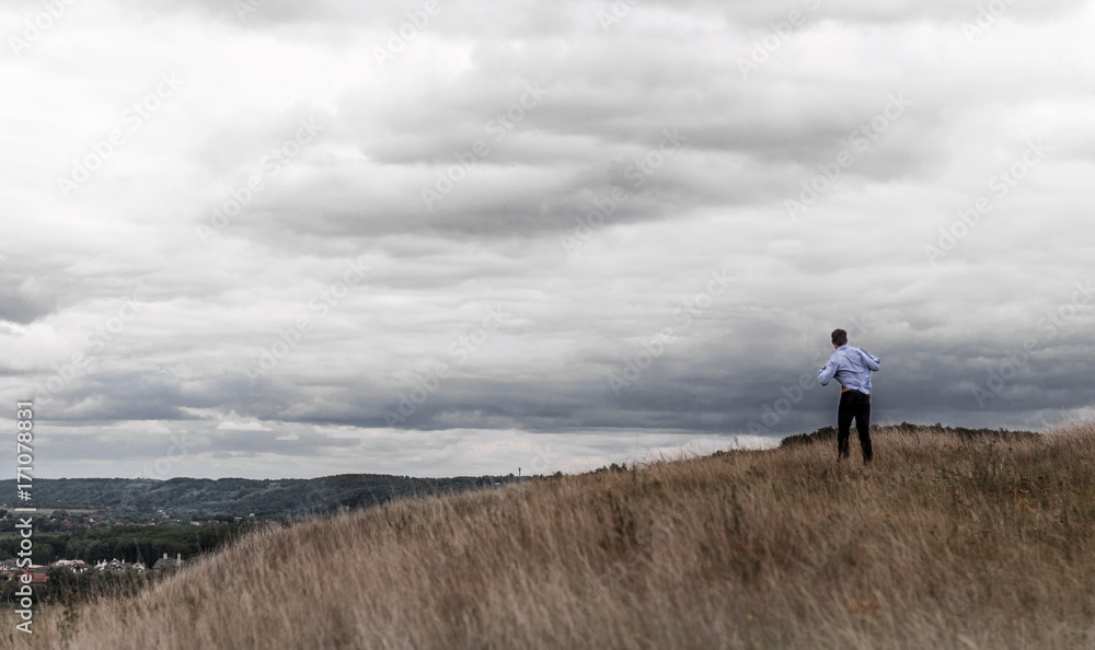 man who feels free in a field on a hill