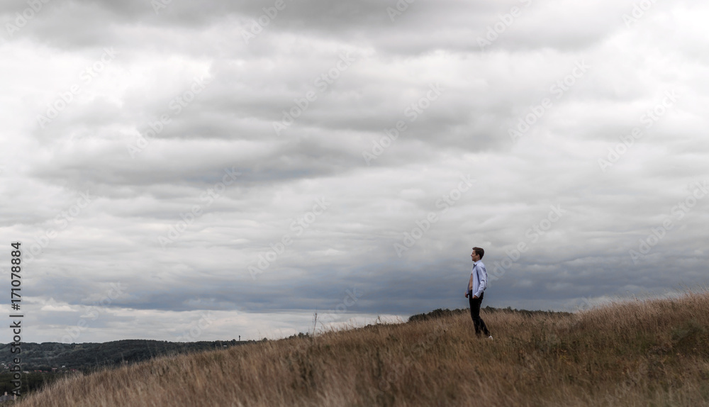 man who feels free in a field on a hill