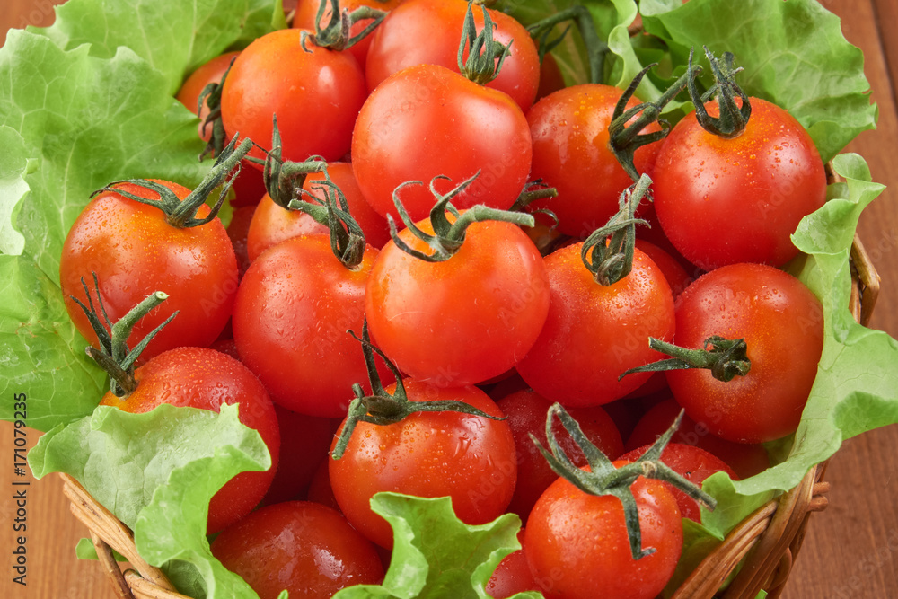 Tomatoes in a wicker basket and green salad leaves