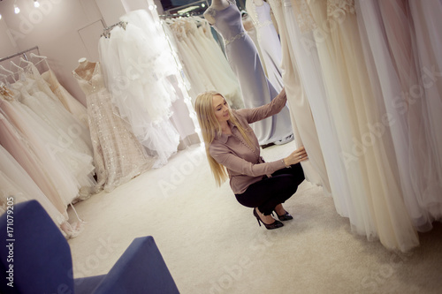 Beautiful girl chooses her wedding dress. Young woman entrepreneur. Portrait in Bridal salon