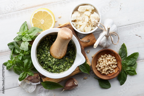 Basil pesto sauce with main ingredients: fresh basil leaves, parmesan cheese, pine nuts, garlic and lemon