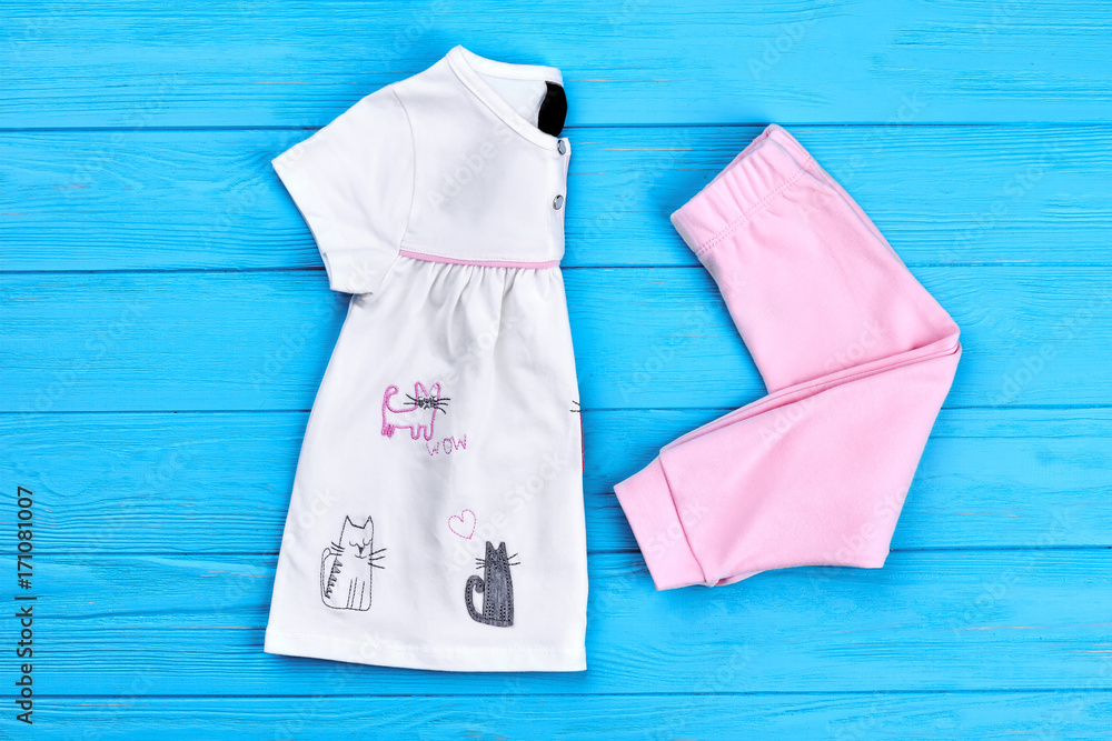 New folded clothes for baby-girl. White dress with colored cartoon cats and  pink leggings for little girls. Natural cotton clothes for girls on sale.  Stock Photo