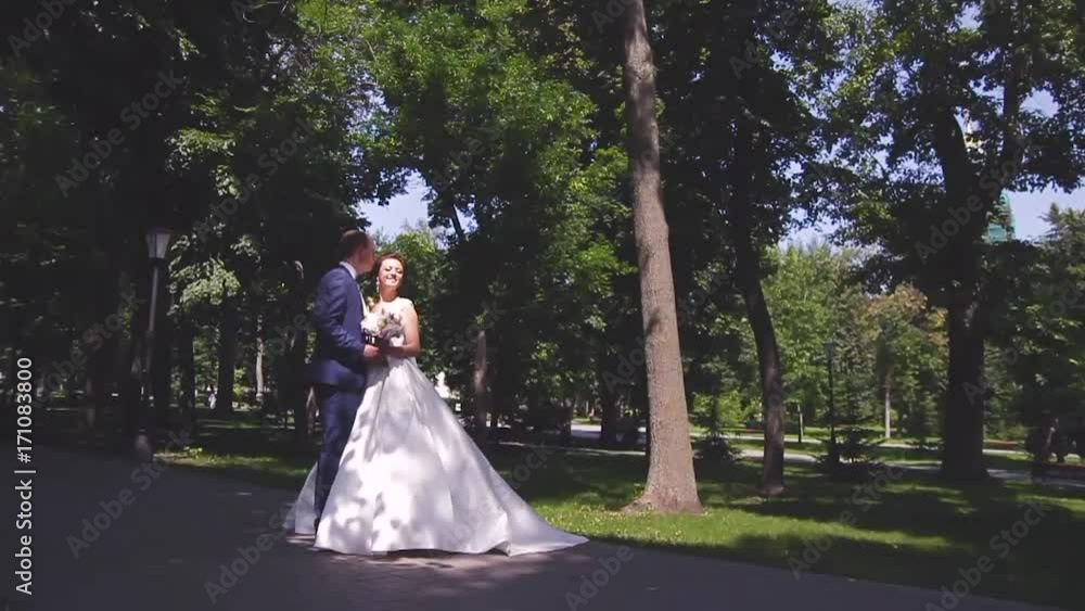 in love a young wedding couple is walking in the park. A husband with his wife in white bride wears a walk in nature in love a young wedding couple is walking in the park. A husband with his wife in white bride wears a walk in nature