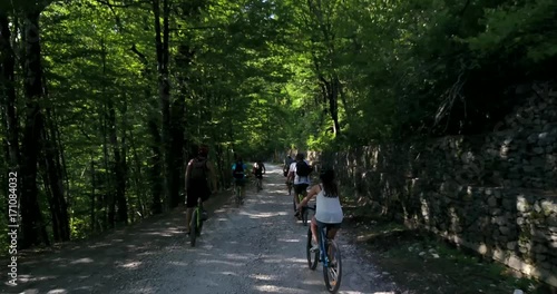 Cyclists ride through the summer forest along the mountain road photo