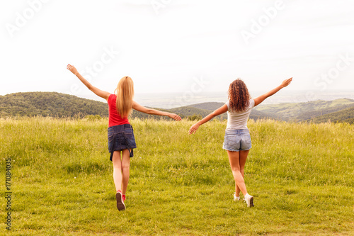 Portrait of two happy young woman on a viewpoint wit her arms outstretched.