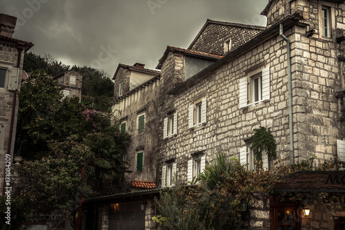 Vintage medieval city street with stone building exterior in overcast day during raining autumn season in old European city Perast with medieval architecture 