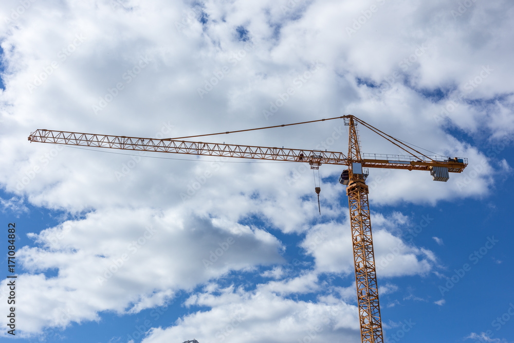 tall crane on construction site clouds blue sky