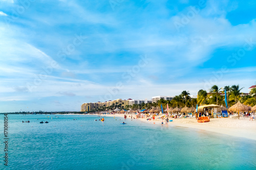 Fototapeta Naklejka Na Ścianę i Meble -  Sandy beach in the High Rise hotel area, Aruba. Unrecognisable tourists enjoy swimming and sunbathing.