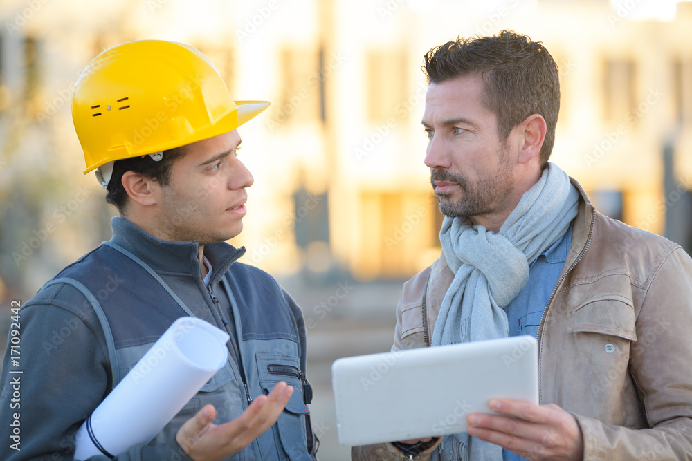 engineer with hard hat using tablet talking to supervisor engineer with hard hat using tablet talking to supervisor