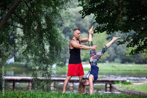 The male instructor helps the girl to do a handstand.
