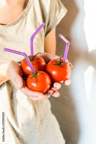 Three Ripe Red Tomatoes with Straws in Woman Hands on Bright Background. Fresh Juice Healthy Food Concept. Tomato as a Vessel with Fresh Juice photo