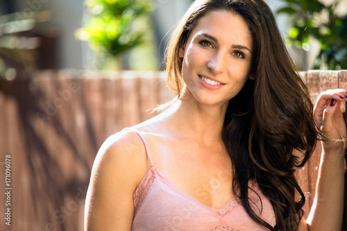 Beautiful headshot of a casual natural brunette female outdoors with healthy skin and teeth