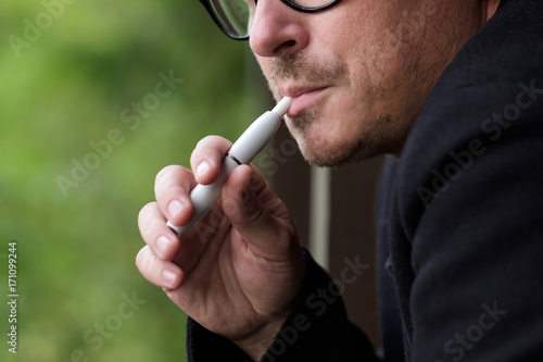Caucasian man smoking modern hybrid cigarette device outdoor