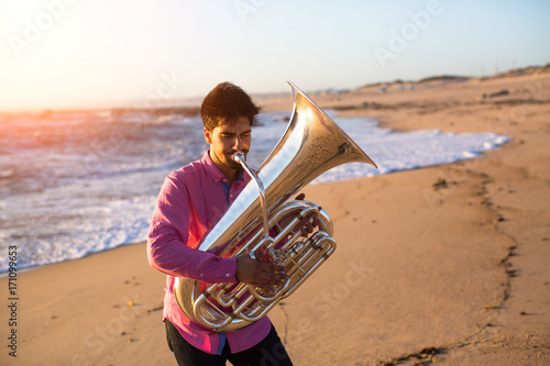 Musician playing the Tuba on the sea coast. photo