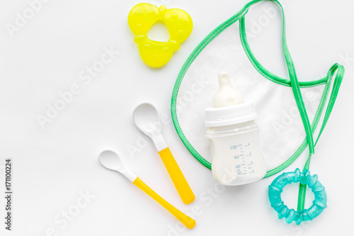 preparation of mixture baby feeding with infant formula powdered milk in bottle with bib on white background top view