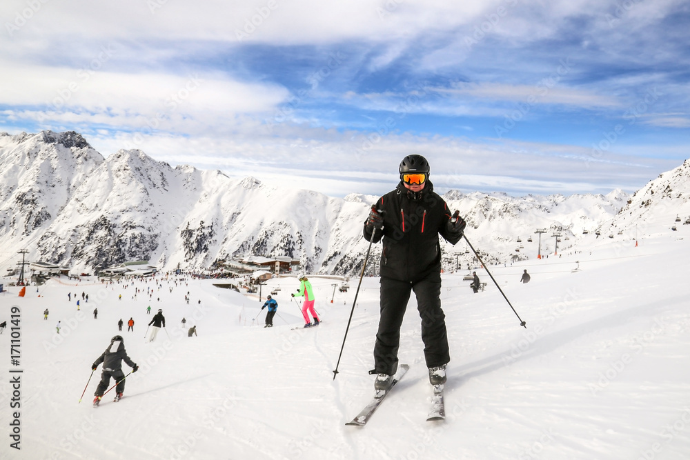 An adult male skier in black skiing sport suite stand on a downhill