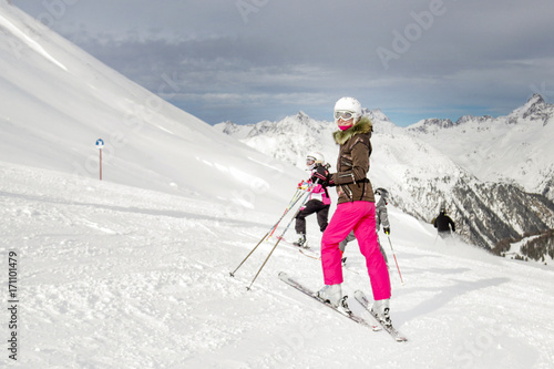 Young beautiful woman skier stand on a top of mountain