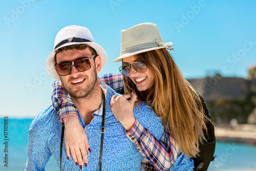 Happy man carrying his girlfriend on a piggyback ride both smiling and looking very happy enjoying their vacation