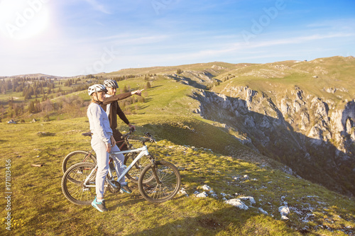 Fototapeta Naklejka Na Ścianę i Meble -  Biker couple with mountain bike pointing in distance at countryside