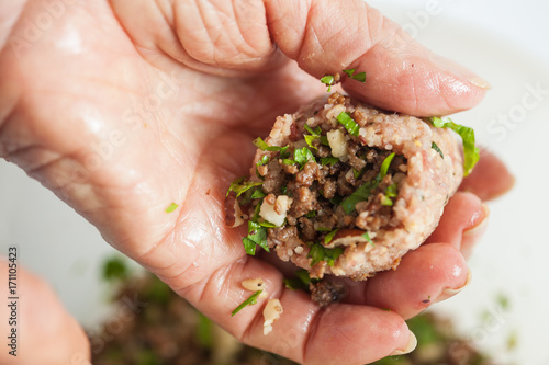 Step by step Levantine cuisine kibbeh preparation : Close up of a senior woman hands filling a kibbeh photo