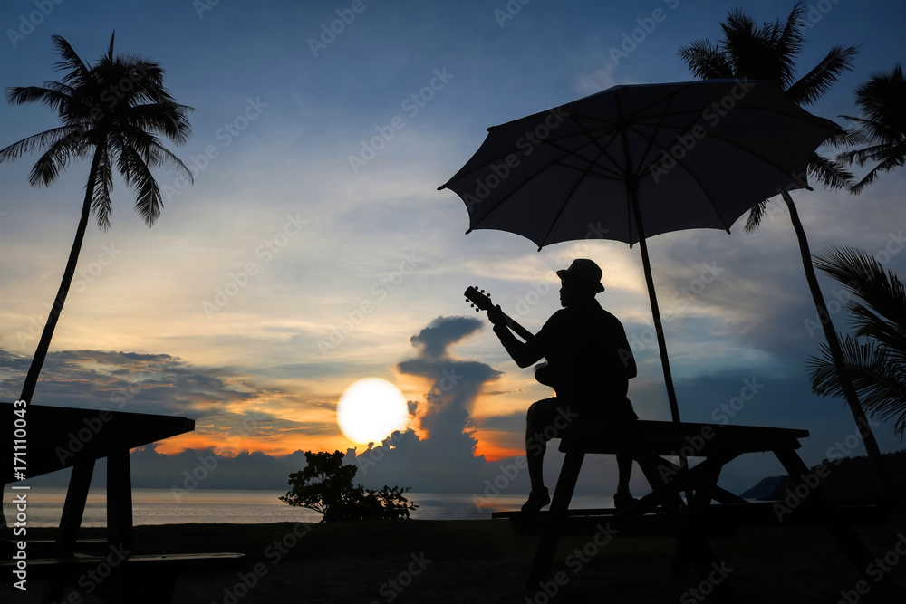 Obraz premium Guitarist on the beach with the sunrise.