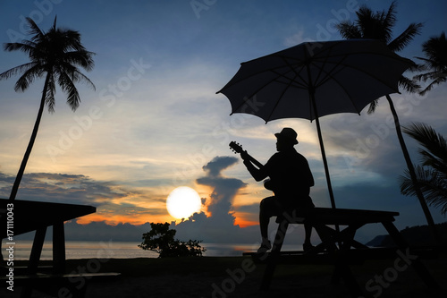 Guitarist on the beach with the sunrise.