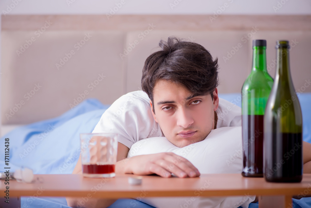 Man alcoholic drinking in bed going through break up depression Man alcoholic drinking in bed going through break up depression