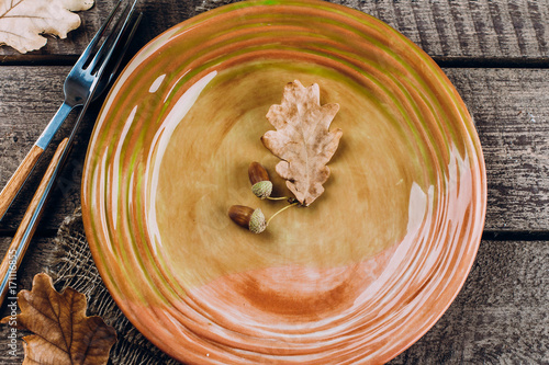 Autumn Table setting. Thanksgiving dinner plate with fork, knife and leaves on rusticwooden table background. Top view, copy space, place for text.