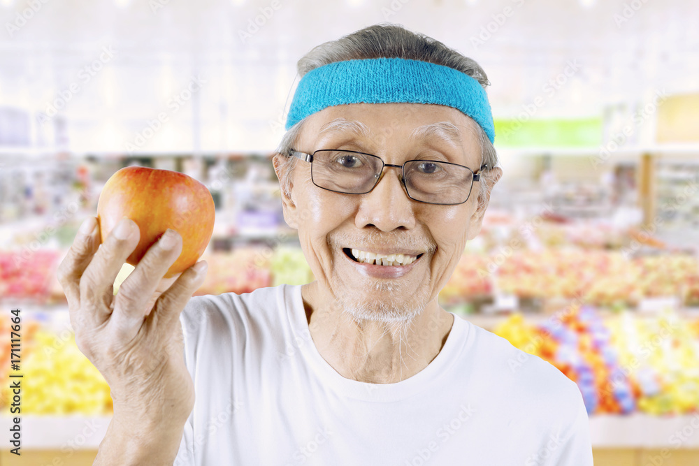 Old man with organic apple in the supermarket