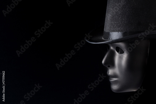 Black mask profile wearing top hat isolated on black background with copy space